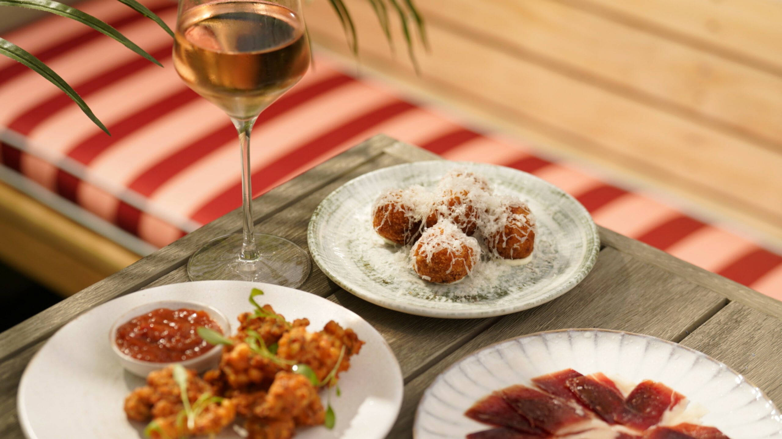 3 plates of sharing dishes with a glass of wine